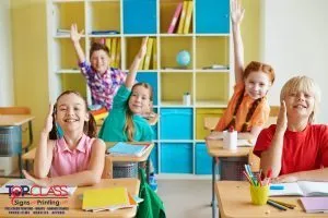 Happy classmates raising hands at lesson